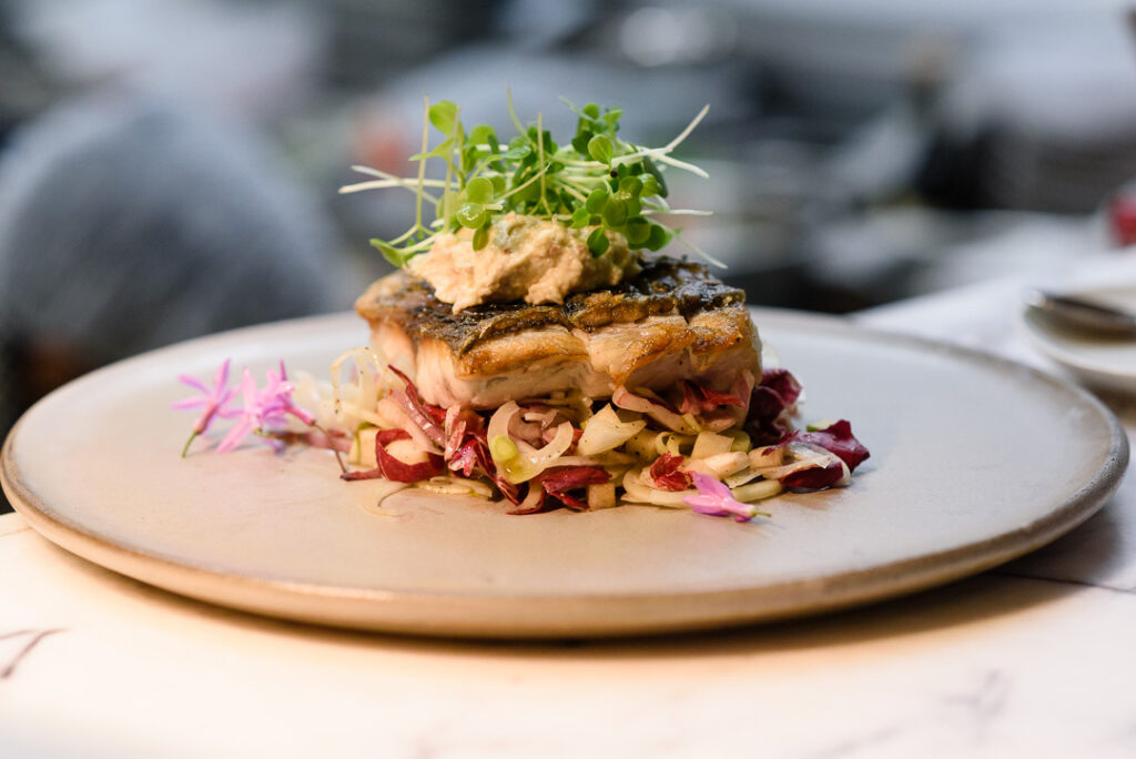 Gourmet pan-seared fish dish topped with fresh microgreens at The Botanica Vaucluse.