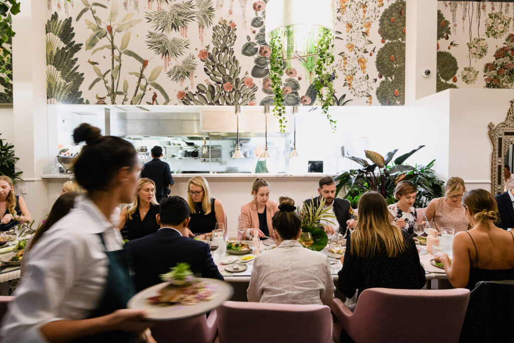 A group of people sitting together and dining at a long table inside The Botanica Restaurant
